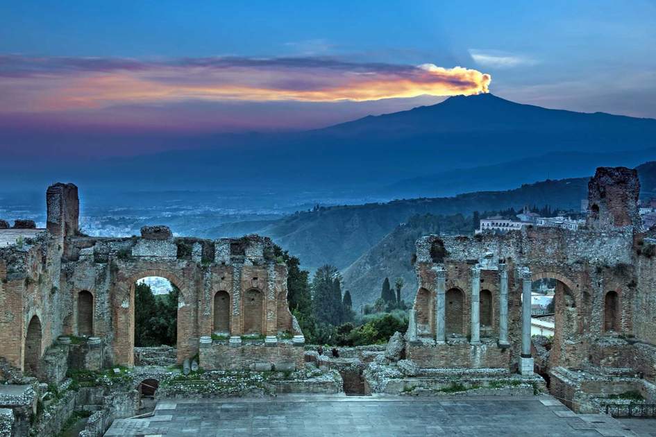 The ruins of the amphitheater on background Etna at sunset