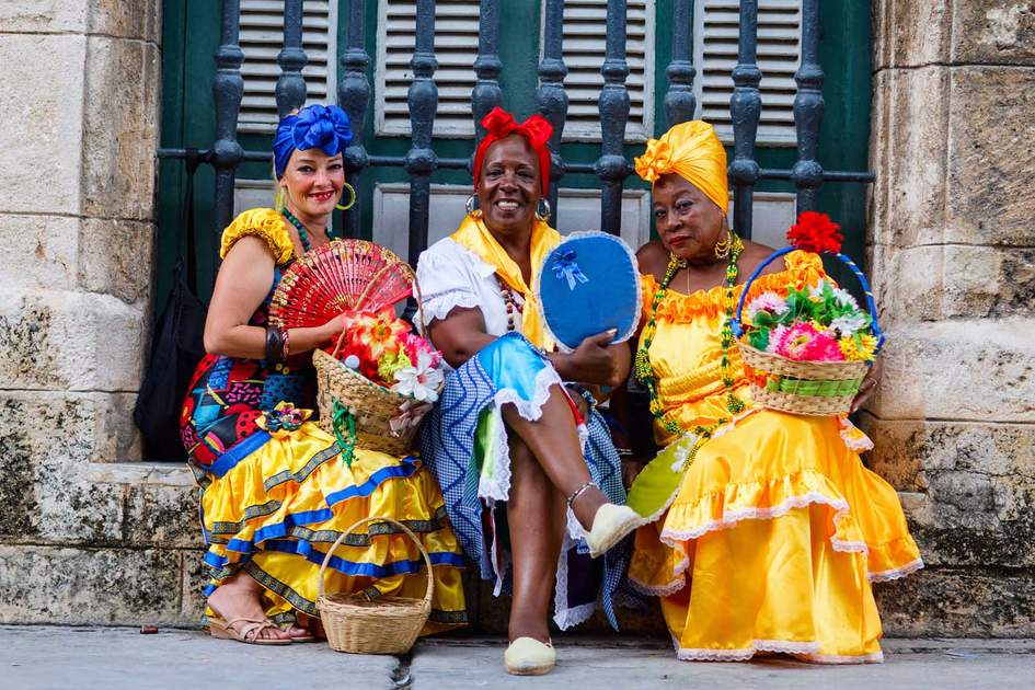 Cuban women in traditional clothing and carrying baskets of flowers in Old Havana. Photo: Shutterstock